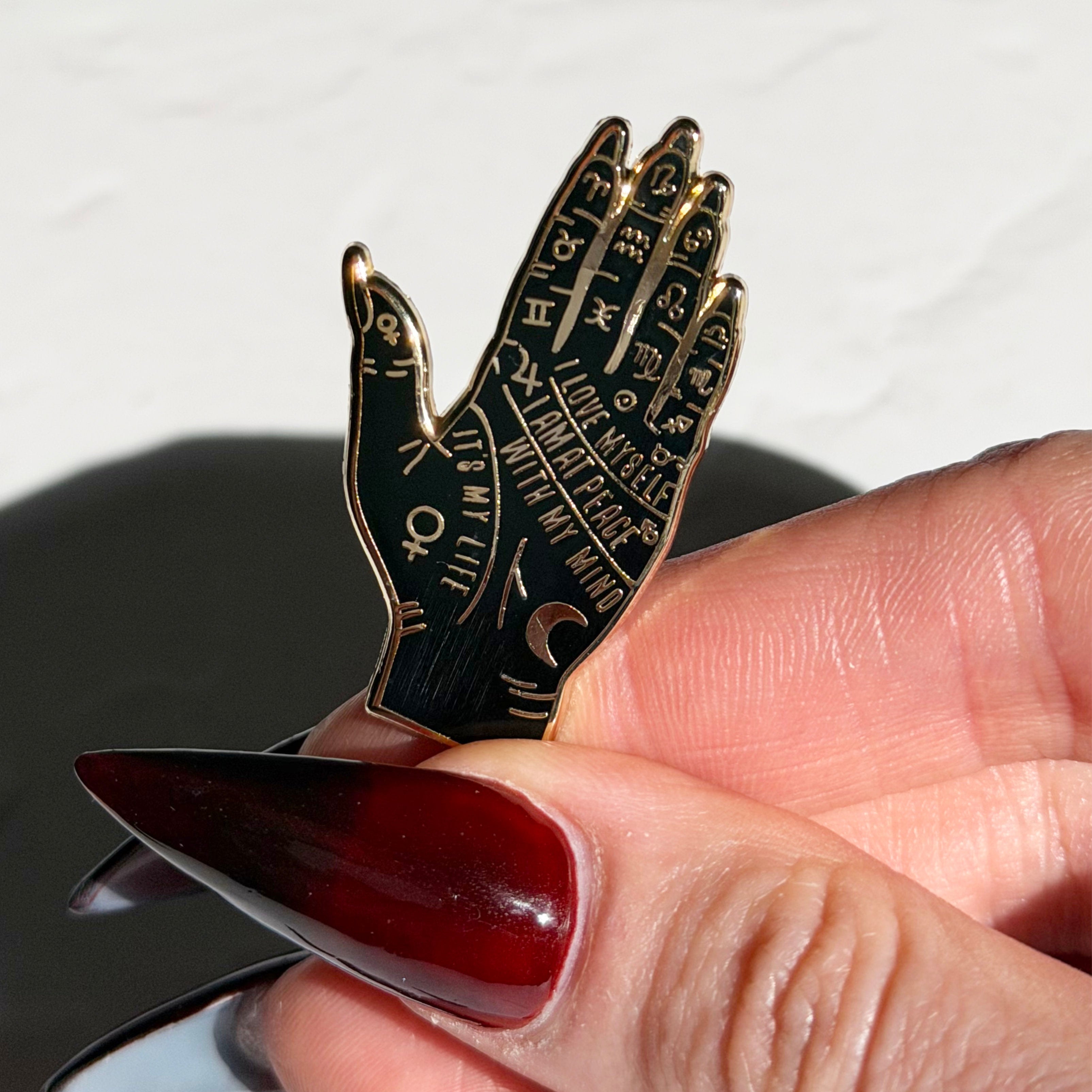 Hand holding a small knife with a decorative handle featuring engraved text.