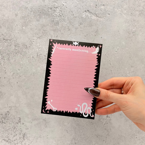 Hand holding a pink card with black border on a gray textured background