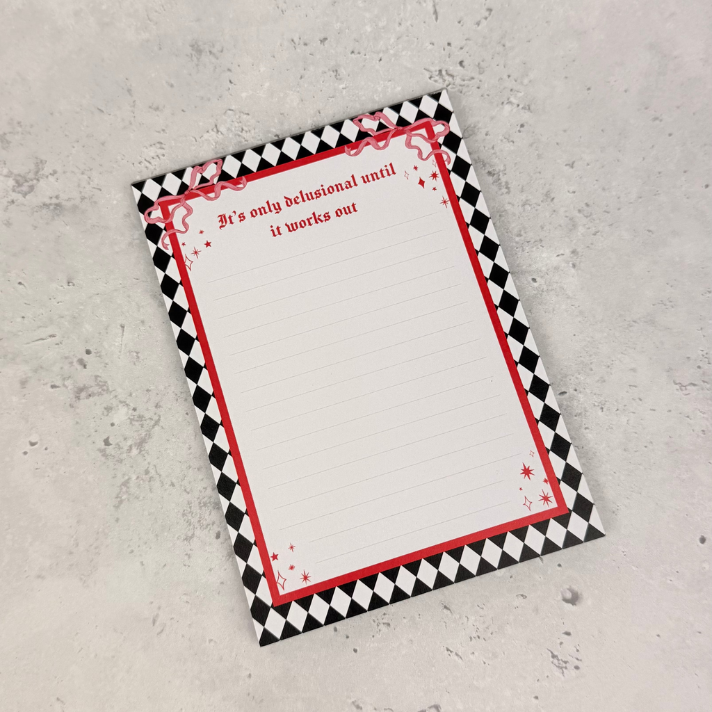 Notebook with black and white checkered border and red accents on a textured gray surface