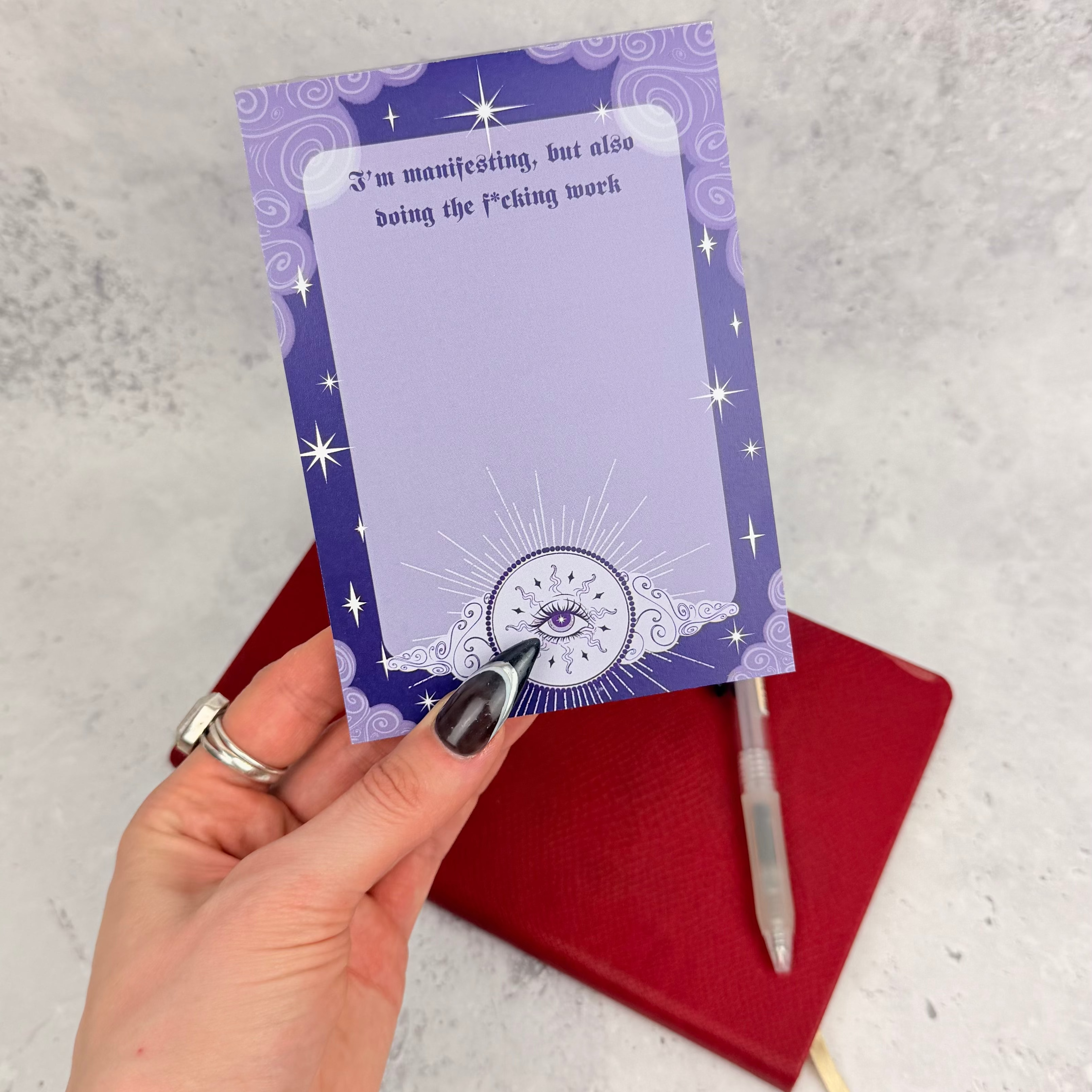 Purple notepad with star designs and a pen on a textured surface