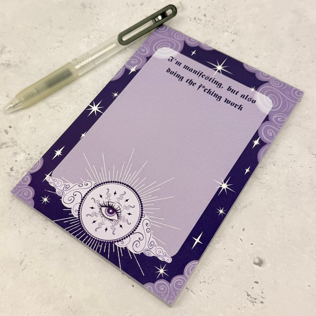 Purple notepad with star designs and a pen on a textured surface