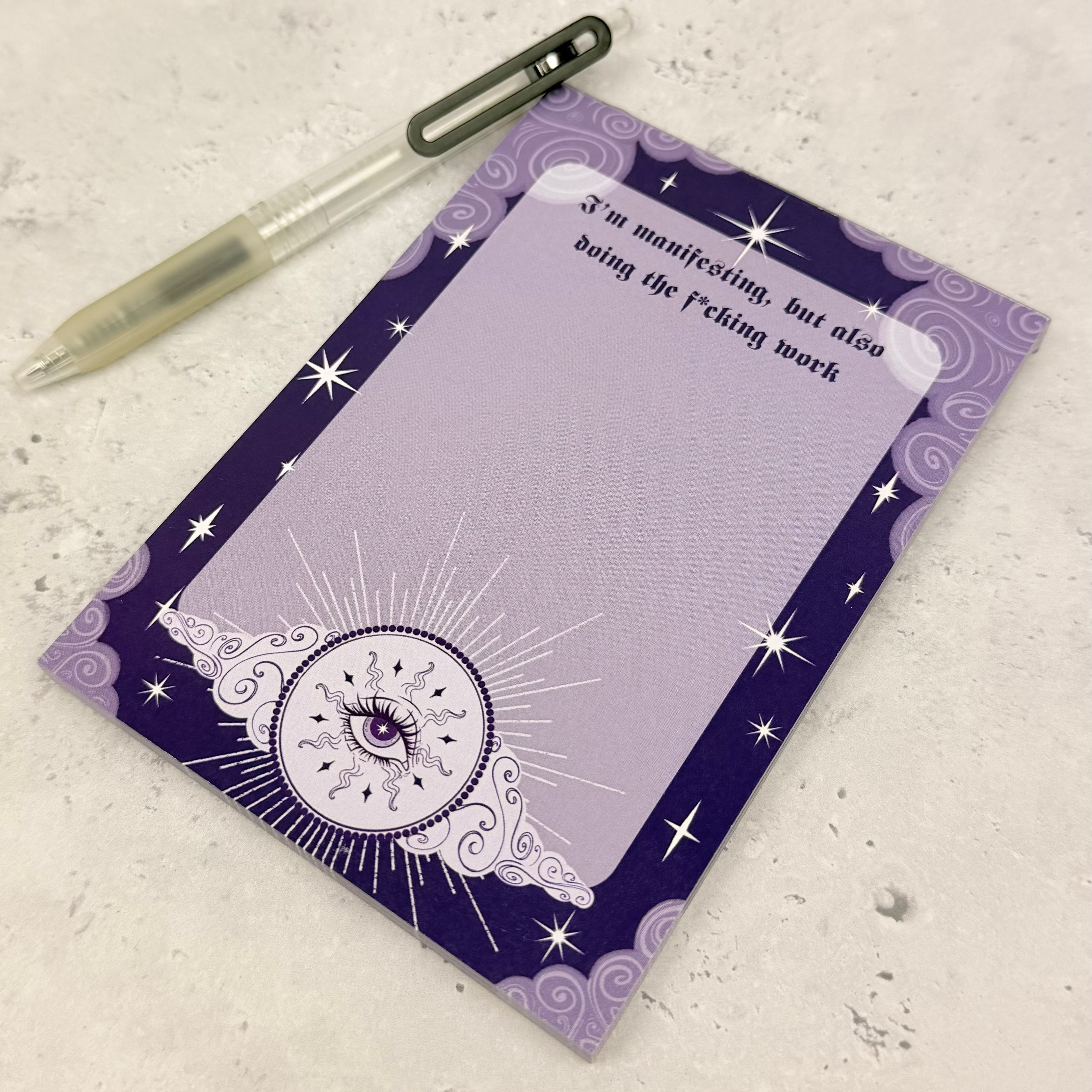 Purple notepad with star designs and a pen on a textured surface