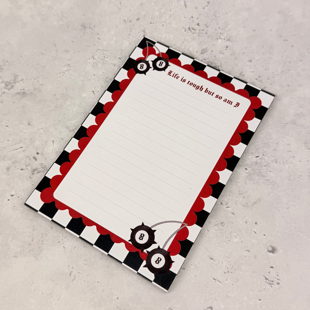 Notebook with a black, red, and white checkered border on a gray surface