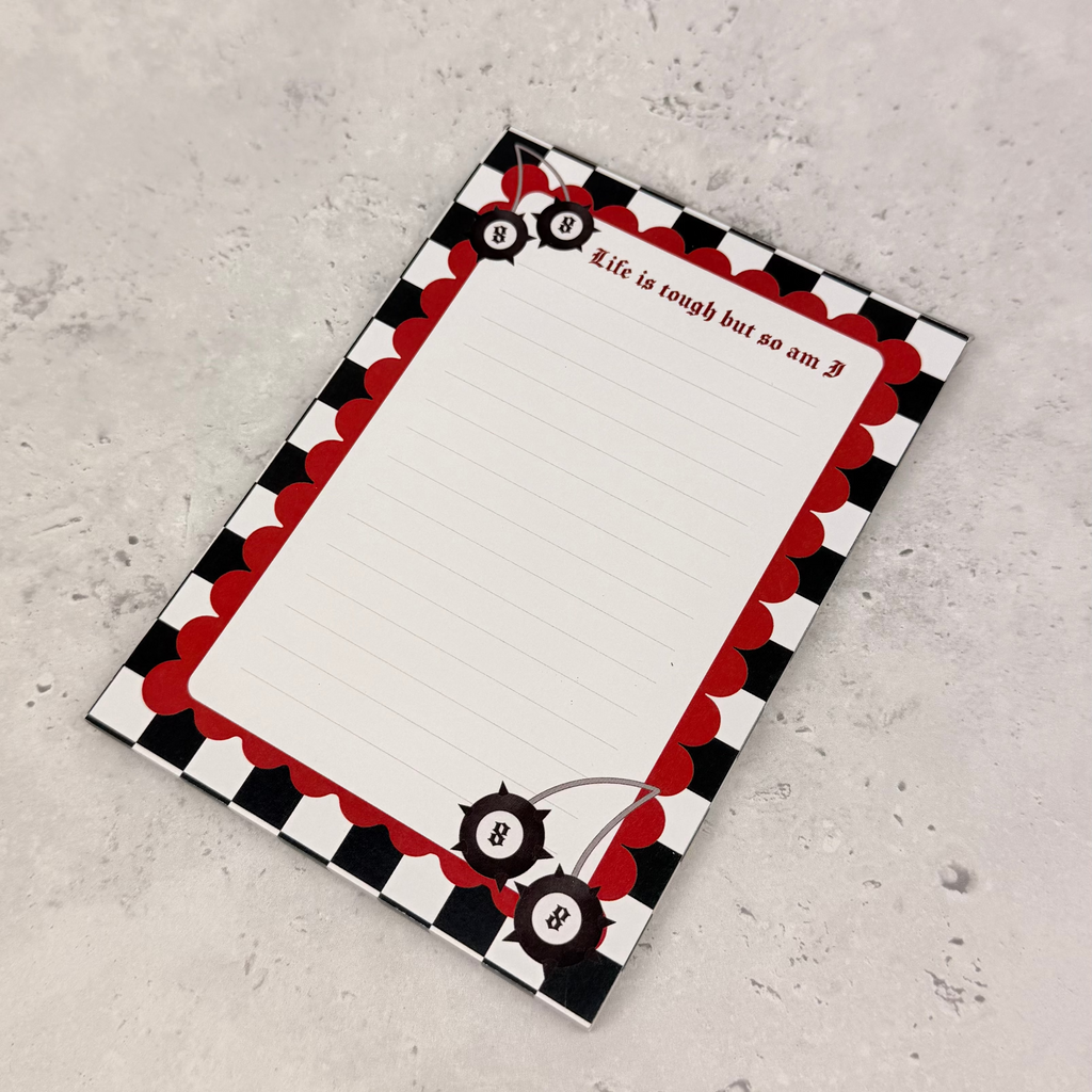 Notebook with a black, red, and white checkered border on a gray surface