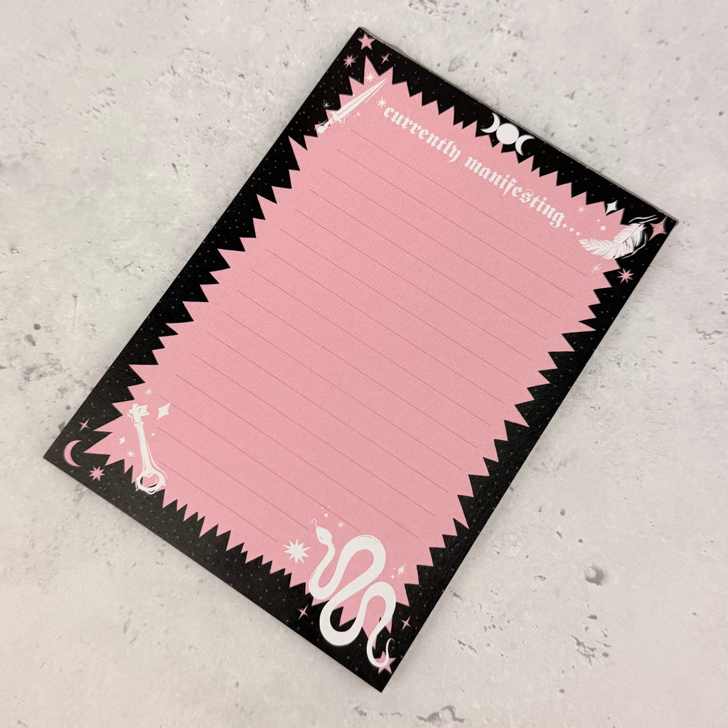 Pink notepad with black border on a gray surface