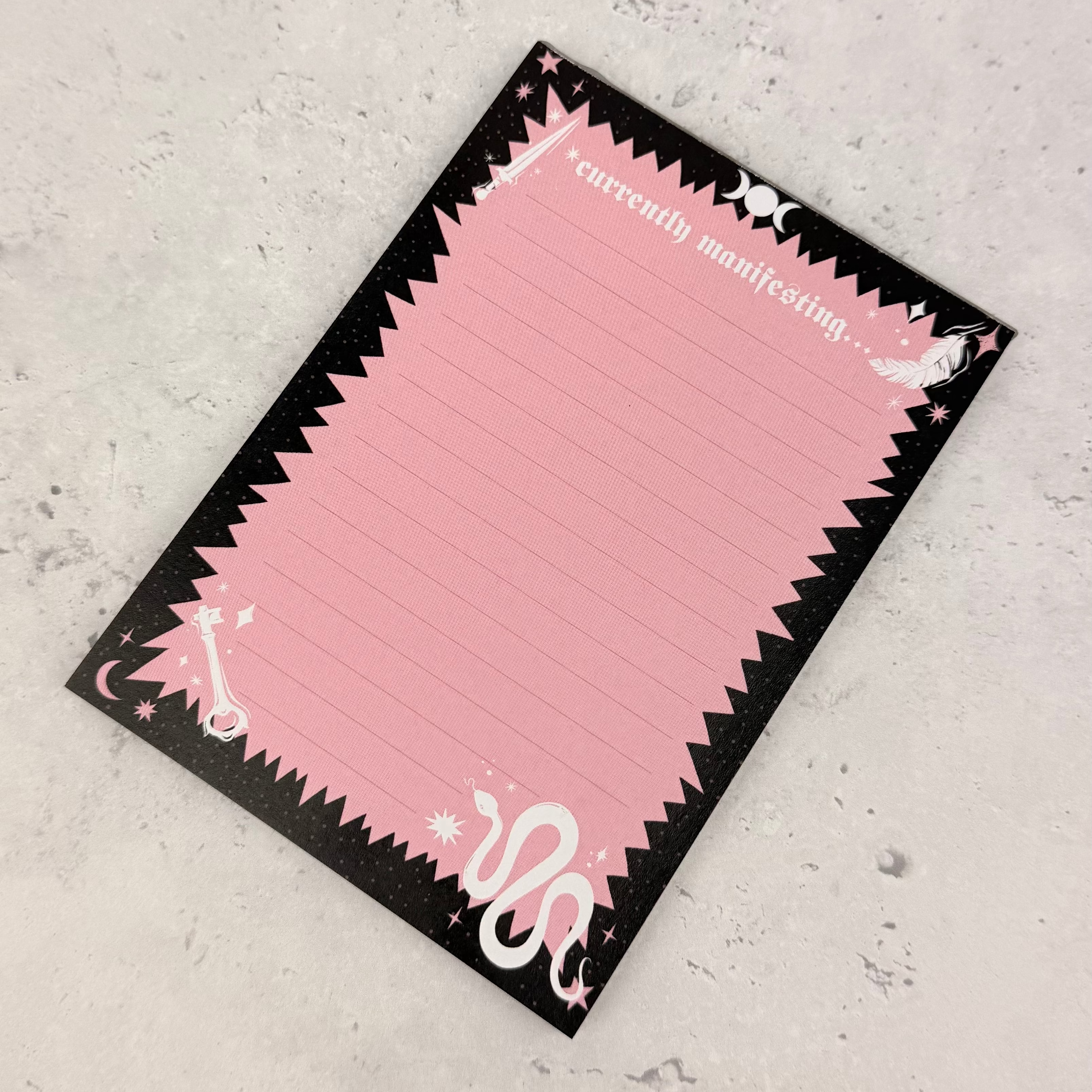 Pink notepad with black border on a gray surface
